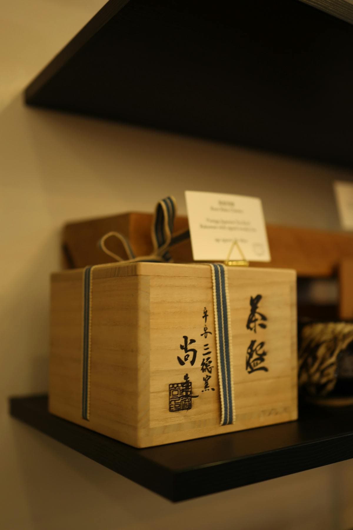 A signed ceramic tea bowl resting in its paulownia gift box